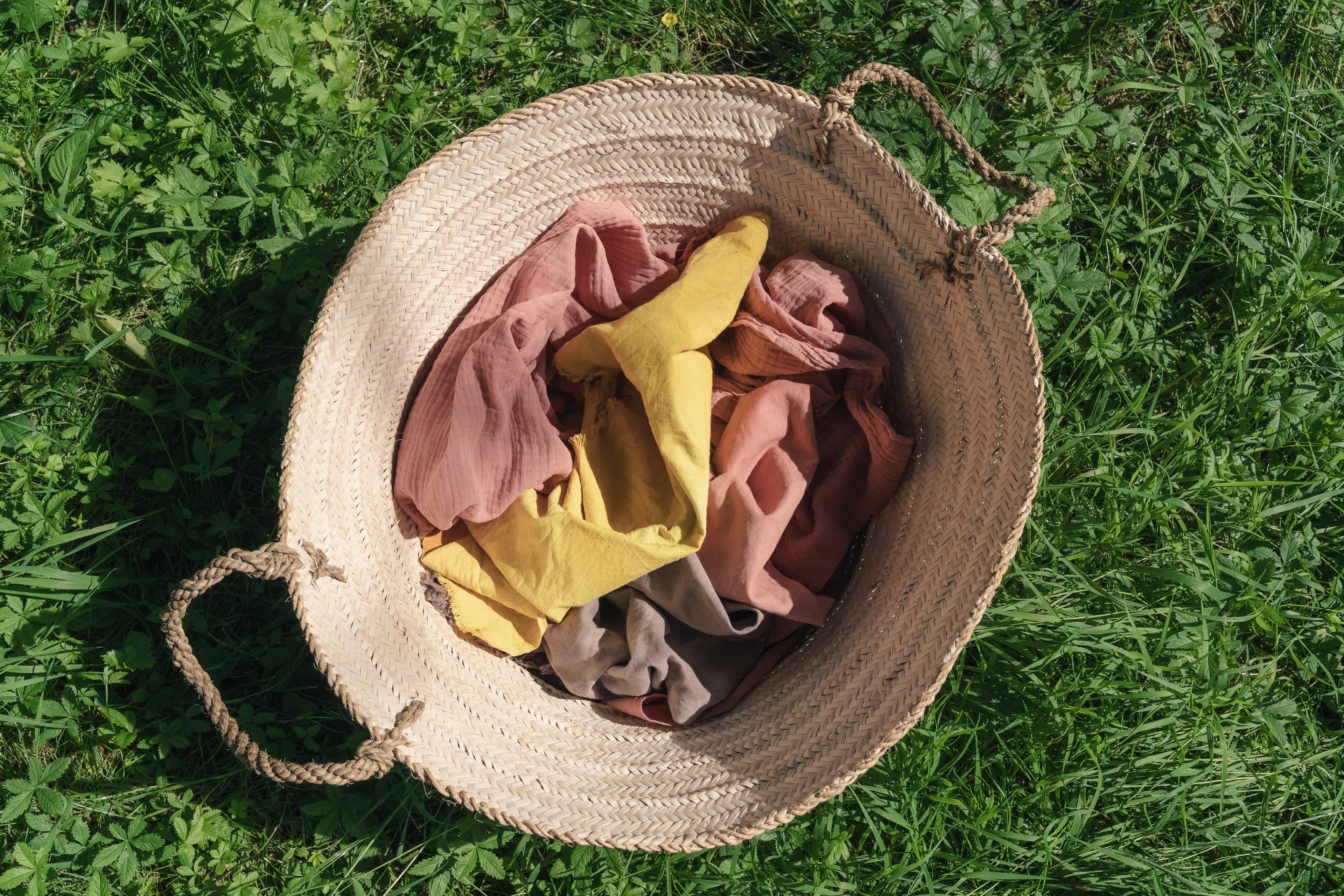 Woven straw basket with hand-dyed fabrics on green grass